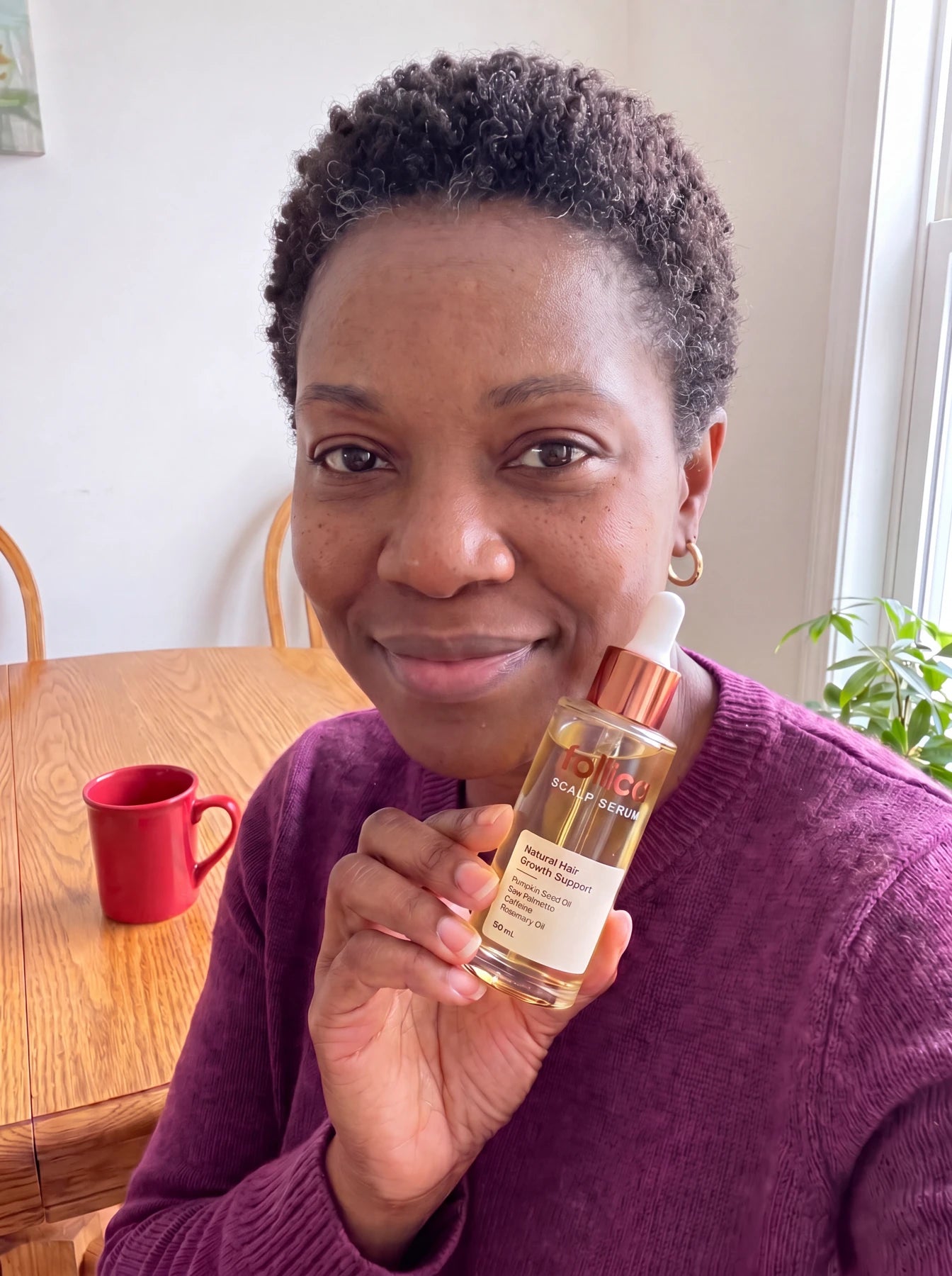 Black woman holding Follica scalp serum